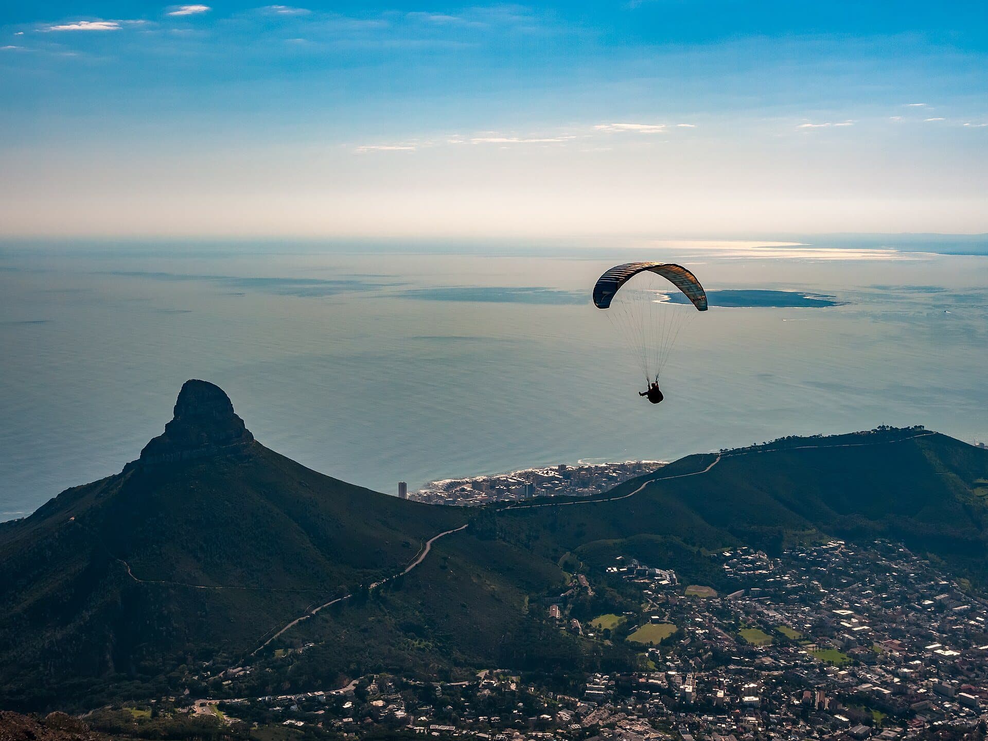 A paraglider drifting above Lion's Head and the Atlantic